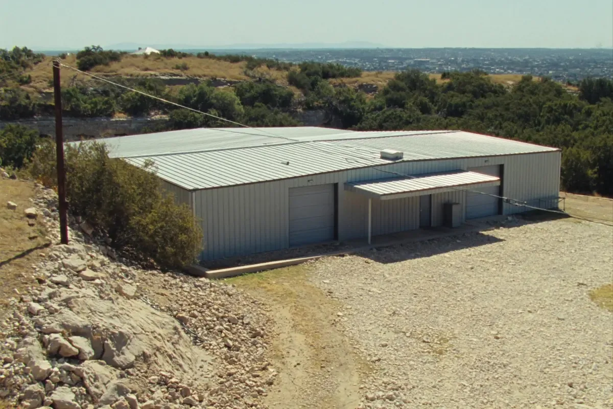 White metal building on a hillside above the city edge in Bexar County, Texas