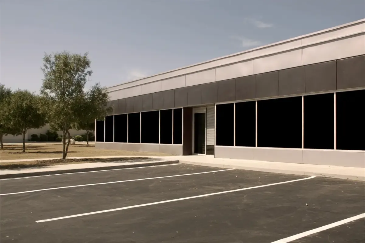 Long commercial metal building with a glass storefront and a striped parking lot in San Antonio, Texas
