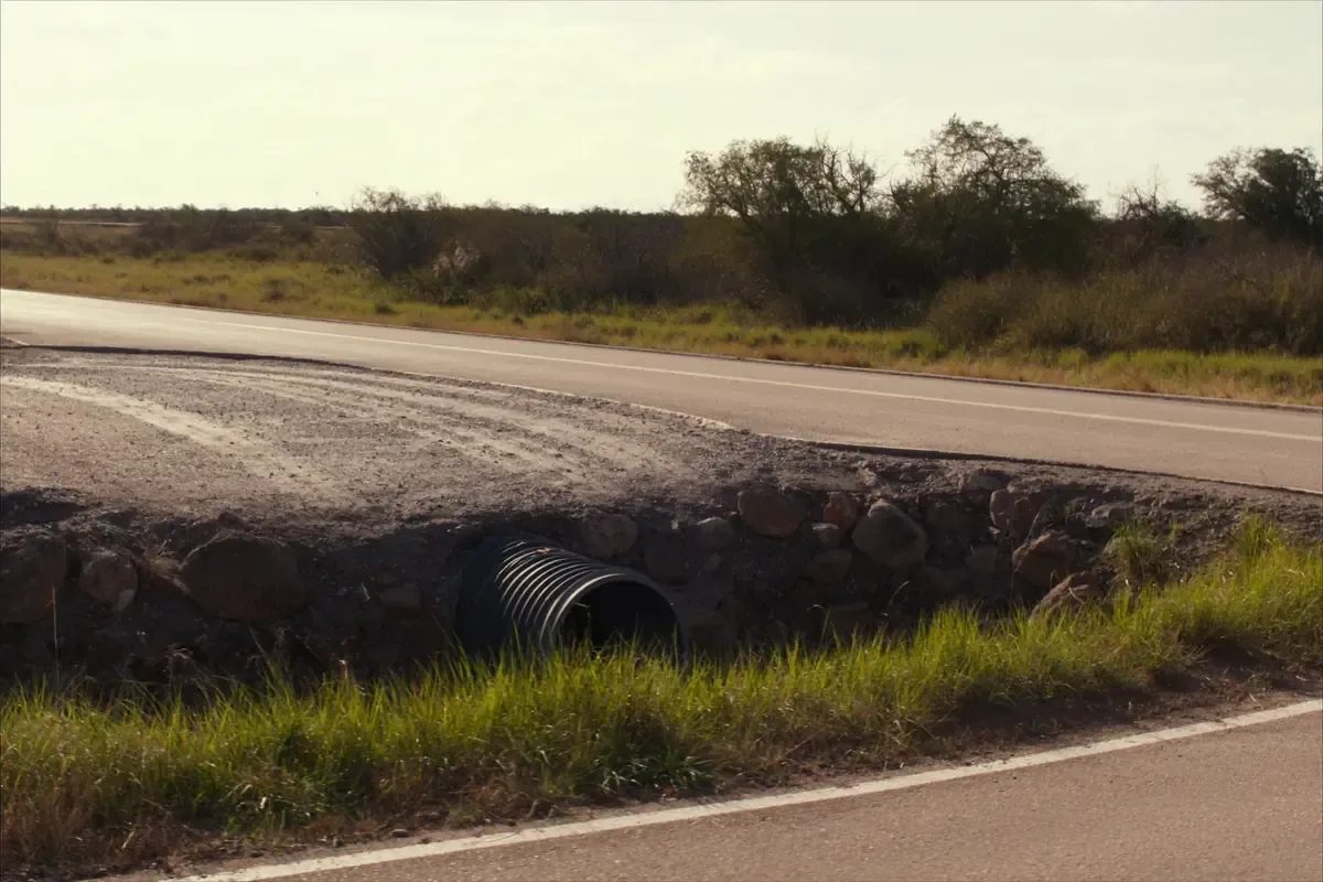 Corrugated metal culvert set in the bar ditch where a driveway meets a rural road in South Texas