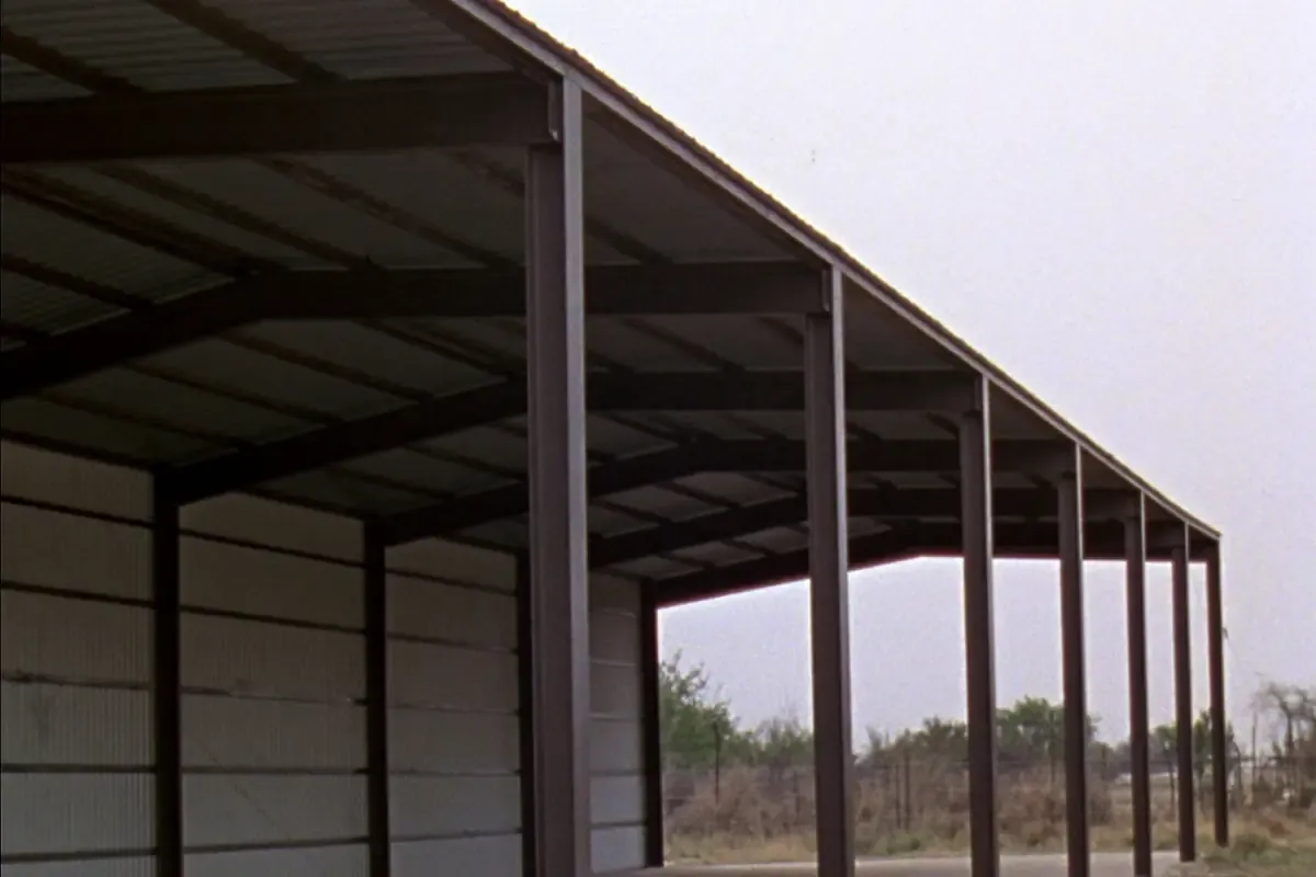 Open front metal storage canopy with empty bays over a concrete slab in South Texas